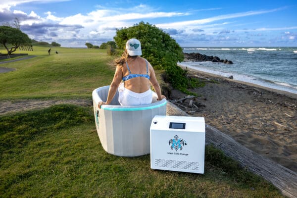 A woman sitting in a tub next to an ice chest.